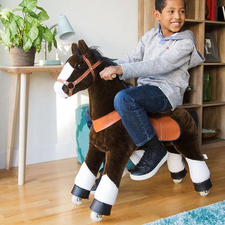 Een vrolijk kind zit op de rug van een rijdend speelgoedpaard.