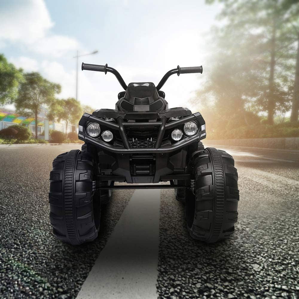 Een elektrische kinderquad staat midden op een asfaltweg, omringd door bomen met het zonlicht dat door de bladeren schijnt.